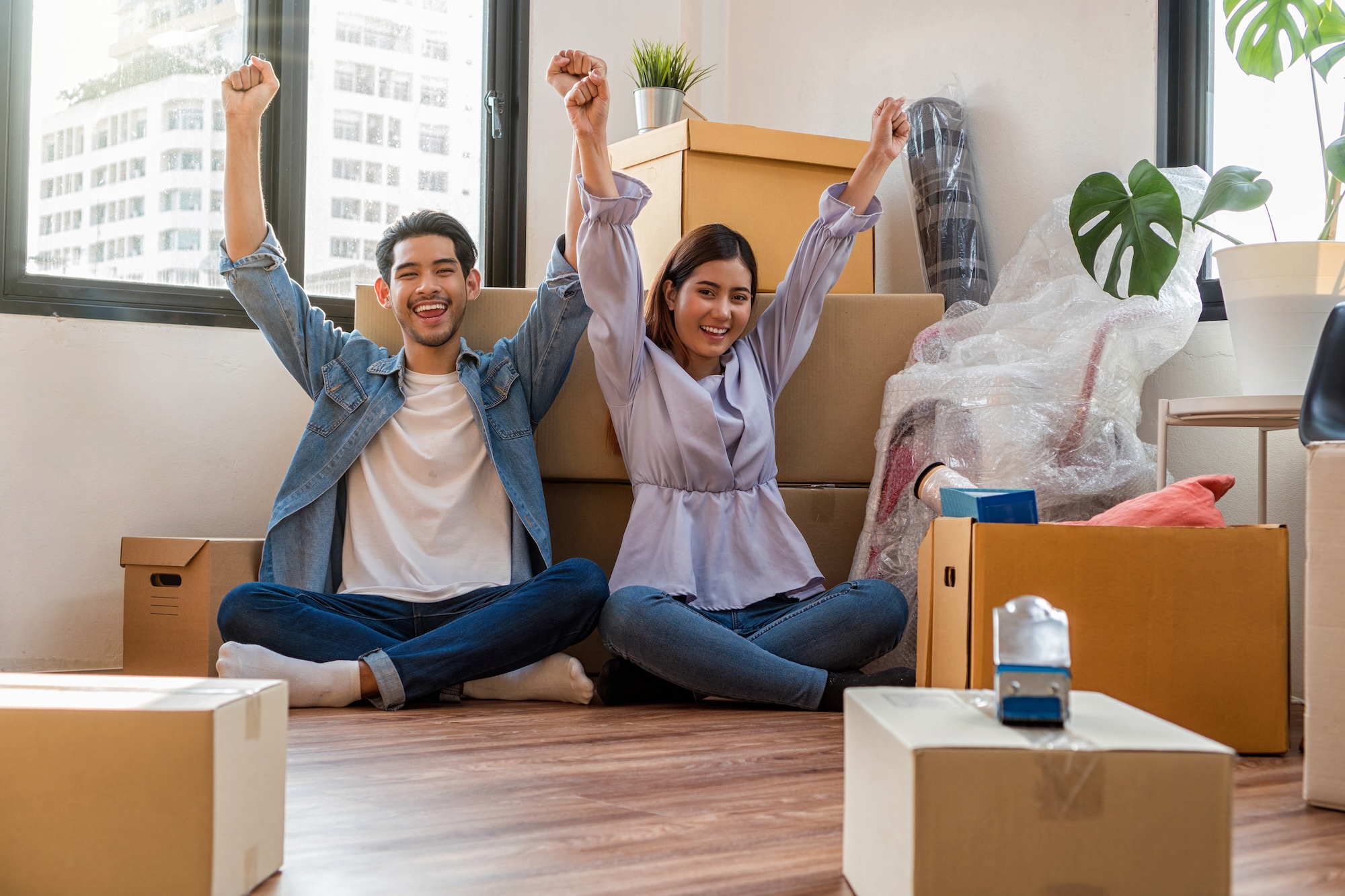 Couple in an apartment with boxes with their arms up